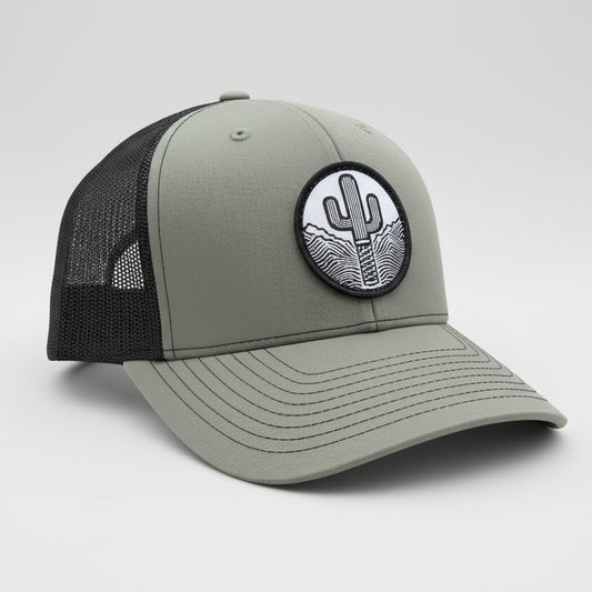Gray cap with black mesh back and cactus patch on a stone surface