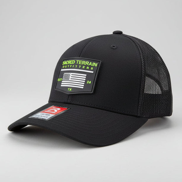 Black cap with brand labels on a stone surface and grass background