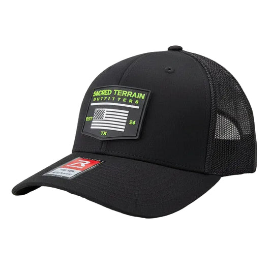 Black cap with brand labels on a stone surface and grass background