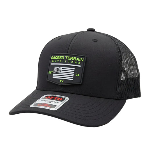 Black cap with mesh back and visible branding on a stone surface