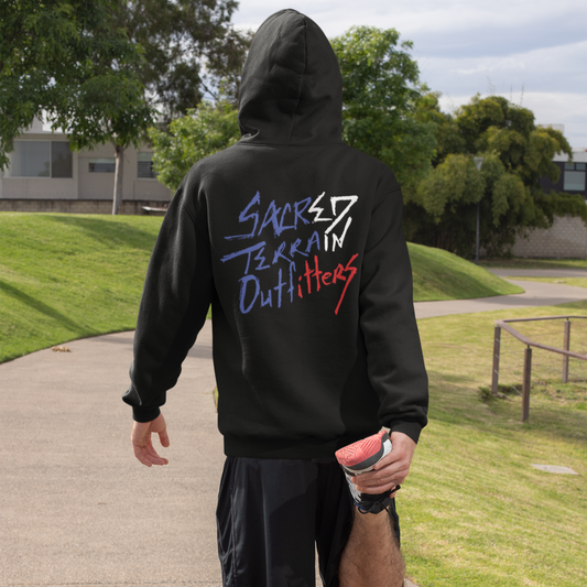 Person wearing a black Sacred Terrain Outfitters hoodie in an outdoor setting